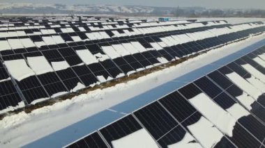 Aerial view of snow melting from covered solar photovoltaic panels at sustainable electric power plant for producing clean electrical energy. Low effectivity of renewable electricity in winter.