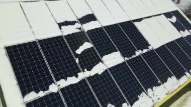 Aerial view of snow melting from covered solar photovoltaic panels installed on house rooftop for producing clean electrical energy. Low effectivity of renewable electricity in nothern region winter.