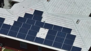 Temiz ekolojik elektrik enerjisi üretmek için mavi güneş fotovoltaik panelleri olan tipik Amerikan binasının çatısı. Emeklilik geliri kavramı için yenilenebilir elektriğe yatırım.
