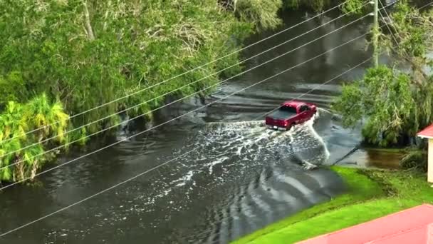 洪水に見舞われたアメリカの通りに移動する車両とフロリダの住宅街の水の家に囲まれている ハリケーンイアンの自然災害の結果 — ストック動画