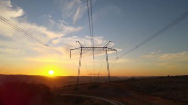 Gün batımında elektrik hatları olan yüksek voltaj kulesi. Elektrik aktarımı.