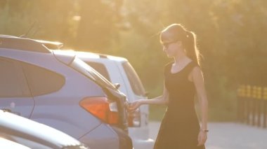 Genç bir kadın sürücü, arabasından bavul çantası çıkarıyor. Seyahat ve tatil kavramı.