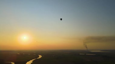 Gün batımında kırsal alanda uçan büyük sıcak hava balonu manzarası..