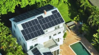 Temiz ekolojik elektrik enerjisi üretmek için mavi güneş fotovoltaik panelleri olan yeni pahalı Amerikan ev çatısının havadan görünüşü. Sıfır emisyon kavramı ile yenilenebilir elektrik.