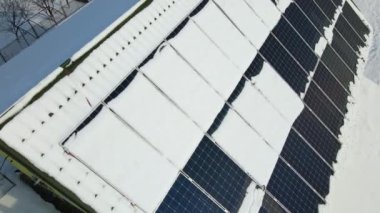 Aerial view of snow melting from covered solar photovoltaic panels installed on house rooftop for producing clean electrical energy. Low effectivity of renewable electricity in nothern region winter.