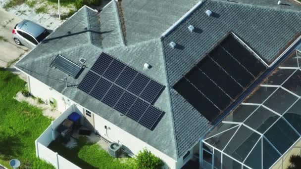 きれいな生態系の電気エネルギーを生成するための青い太陽光発電パネルと典型的なアメリカの建物の屋根の空中ビュー 退職所得の概念のための再生可能エネルギーへの投資 — ストック動画