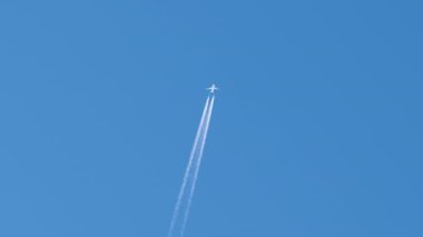 Mesafeli yolcu jet uçağı açık mavi gökyüzünde yüksek irtifada uçarken ardında beyaz duman izi bırakıyor. Hava taşımacılığı kavramı.