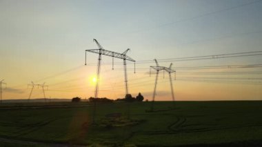 Gün batımında elektrik hatları olan yüksek voltaj kuleleri..