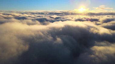 Yükseklerden gökyüzü manzarası. Akşamları yoğun, kabarık kümülüs bulutları uçuşuyor. Uçak penceresinden gün batımı inanılmaz..