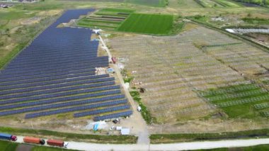 Elektrik santralinin inşaat halindeki hava görüntüsü. Kamyon, elektrik enerjisi üretmek için metal çerçevedeki güneş panelleri için montaj parçaları dağıtıyor. Yenilenebilir elektriğin geliştirilmesi.