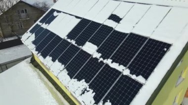 Aerial view of house roof with solar panels covered with snow melting down in winter end for producing clean energy. Concept of low effectivity of renewable electricity in northern region.