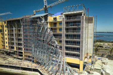 Aerial view of ruined by hurricane Ian construction scaffolding on high apartment building site in Port Charlotte, USA. clipart