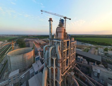 Yüksek fabrika yapısı olan çimento fabrikası ve endüstriyel üretim bölgesinde kule vinçleri var. Üretim ve küresel sanayi kavramı.