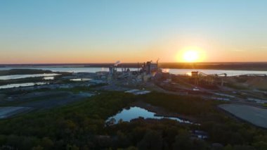 Üretim sürecinden kaynaklanan dumanlı büyük fabrika yapısı üretim sahasında çevre kirliliği yaratan atmosferi yükseltiyor. Gün batımında sanayi bölgesi.