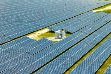 Temiz elektrik enerjisi üretmek için sıra sıra güneş fotovoltaik panelleri olan sürdürülebilir büyük elektrik santralinin havadan görünüşü. Sıfır emisyonlu yenilenebilir elektrik kavramı.