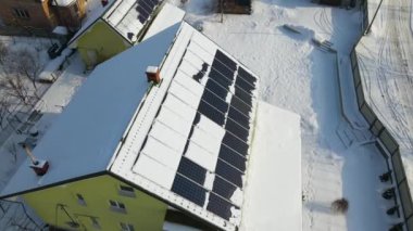 Aerial view of house roof with solar panels covered with snow melting down in winter end for producing clean energy. Concept of low effectivity of renewable electricity in northern region.