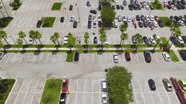 Aerial view of large parking lot with many parked colorful cars. Carpark at supercenter shopping mall with lines and markings for vehicle places and directions.