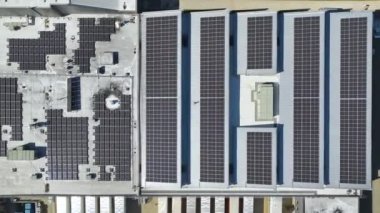 Sanayi binasının çatısına yeşil ekolojik elektrik üretmek için monte edilmiş mavi fotovoltaik panelli güneş enerjisi santralinin hava görüntüsü. Sürdürülebilir enerji konsepti üretimi.