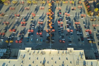 Hava manzaralı alışveriş merkezi ve park yerinde park yerleri ve yönler için çizgiler ve işaretler olan bir sürü renkli araba. Bir alışveriş merkezinin önünde araçlar için yer.