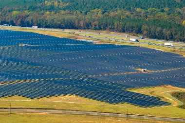 Temiz elektrik enerjisi üretmek için birçok sıra güneş fotovoltaik paneli bulunan sürdürülebilir büyük elektrik santralinin havadan görünüşü. Sıfır emisyon kavramı ile yenilenebilir elektrik.