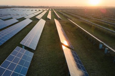 Akşamları temiz elektrik enerjisi üretmek için sıra sıra güneş fotovoltaik panelleri olan sürdürülebilir büyük elektrik santralinin havadan görünüşü. Sıfır emisyonlu yenilenebilir elektrik kavramı.