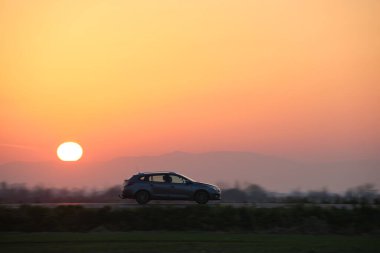 Gün batımında şehir içi yolda hızlı giden bir araba. Akşamları otoyol trafiği.