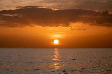 Okyanus batımı. Büyük beyaz güneş dramatik parlak gökyüzü arka planında, yumuşak akşam ufku denizin üstünde karanlık su üzerinde..