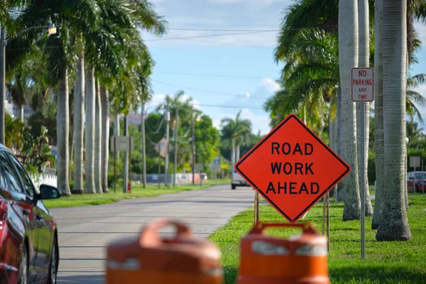 Road work ahead sign on street site as warning to cars about construction and utility works.