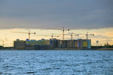 Yüksek konutlu apartman şantiyesinde vinç kaldırma. Deniz kıyısında gayrimenkul geliştirme.