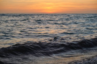 Dramatic red ocean waves at sunset with soft evening sea dark water.