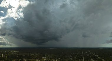 Landscape of dark ominous clouds forming on stormy sky during heavy thunderstorm over rural town area.