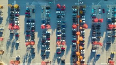 Bir alışveriş merkezinin önündeki otoparkta park edilmiş birçok arabanın üst görüntüsü. Tüketim ve piyasa ekonomisi kavramı.