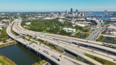 Jacksonville şehrinin hava manzarası. Yüksek ofis binaları ve hızlı araba ve kamyonlarla Amerikan otoyolu kavşağı. ABD ulaşım altyapısının üstünden görüntüle.