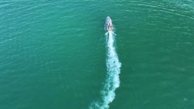 Dalgalanma yüzeyi ile deniz dalgaları üzerinde yüzen beyaz yatın havadan görünüşü. Motorlu tekne okyanusta hareket halinde..