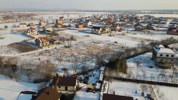 寒い冬に農村郊外の町エリアで雪に覆われた屋根を持つ民家の空中ビュー — ストック動画