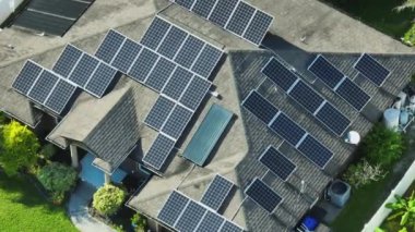 Dış havalandırma ünitesi ve çatısı güneş fotovoltaik panellerle kaplı, temiz elektrik enerjisi üretmek için standart bir Amerikan yerleşim evi.