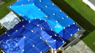 Asfalt kiremitlerin yerine konana kadar yağmur suyu sızıntılarına karşı koruyucu branda örtüleriyle kaplı çatı sızdırma manzarası. Florida 'daki Ian Kasırgası' nın yol açtığı çatı hasarı.