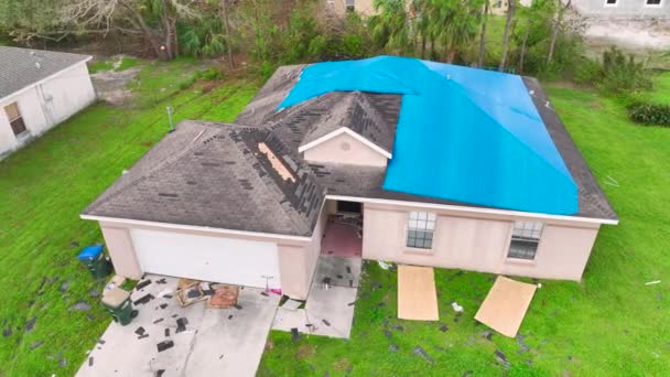アスファルトの帯状疱疹の交換まで雨の水漏れに対する保護タープシートで覆われた家の屋根を漏洩のトップビュー フロリダ州のハリケーンイアンの余波として屋上の建物の損傷 — ストック動画