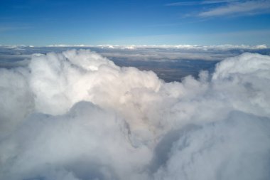 Dünya 'nın yüksek irtifasındaki uçak penceresinden hava manzarası beyaz kabarık kümülüs bulutlarıyla kaplı..