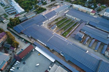 Sanayi binasının çatısına yeşil ekolojik elektrik üretmek için monte edilen mavi fotovoltaik güneş panellerinin hava görüntüsü. Sürdürülebilir enerji konsepti üretimi.