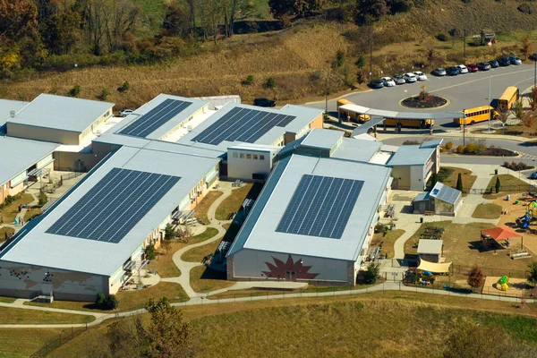Aerial view of american school building with rooftop covered with photovoltaic solar panels for production of electric energy.