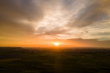 Parlak renkli günbatımı gökyüzü, batan güneş ve canlı bulutlar, karanlık manzaranın üzerinde..
