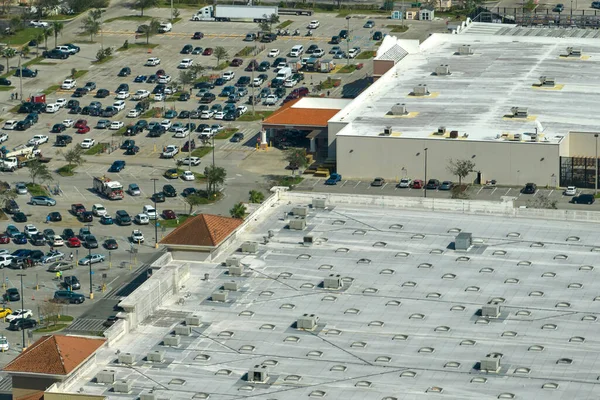 View from above of american grocery store with many parked cars on parking lot with lines and markings for parking places and directions. Place for vehicles in front of a strip mall center.
