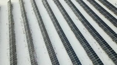 Aerial view of snow melting from covered solar photovoltaic panels at sustainable electric power plant for producing clean electrical energy. Low effectivity of renewable electricity in winter.