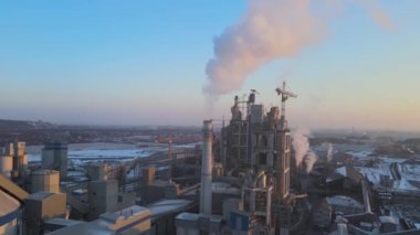 Yüksek beton fabrikası ve endüstriyel üretim alanında kule vinçleri olan çimento fabrikasının havadan görüntüsü. Sera gazı bacası atmosferi kirletiyor. Üretim ve küresel sanayi kavramı