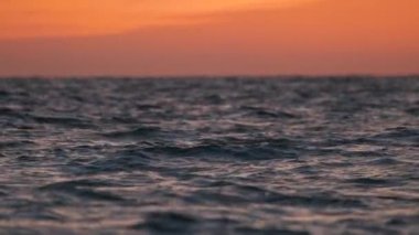 Dramatic red ocean waves at sunset with soft evening sea dark water.