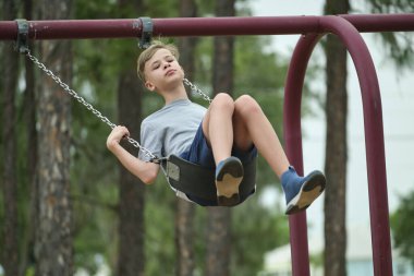 Genç yakışıklı delikanlı yaz tatillerinde tek başına salıncakta sallanıyor..