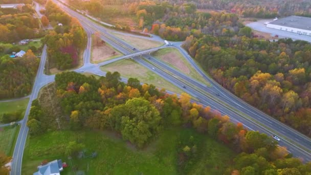 高速道路の空中ビューは 日没時にノースカロライナ州黄金の秋の季節に高速移動交通車やトラックとの交差点を越えます アメリカの州間交通インフラ — ストック動画