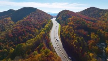 Aerial view of I-40 freeway in North Carolina leading to Asheville through Appalachian mountains in golden fall with fast moving trucks and cars. Interstate transportation concept.