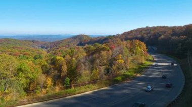 View from above of national freeway route in North Carolina leading thru Appalachian mountains with yellow fall woods and fast moving trucks and cars. Interstate transportation concept.